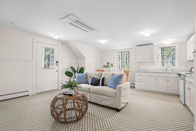 living room with visible vents, baseboard heating, wainscoting, and vaulted ceiling