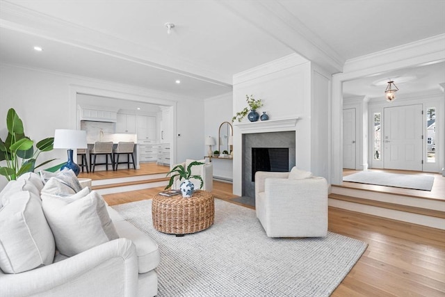 living area featuring crown molding, a fireplace with flush hearth, wood finished floors, and recessed lighting