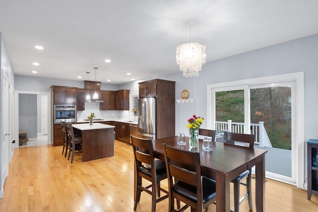 dining area with an inviting chandelier and light hardwood / wood-style flooring