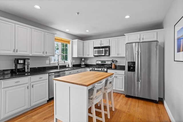 kitchen featuring a kitchen breakfast bar, sink, white cabinets, a center island, and stainless steel appliances