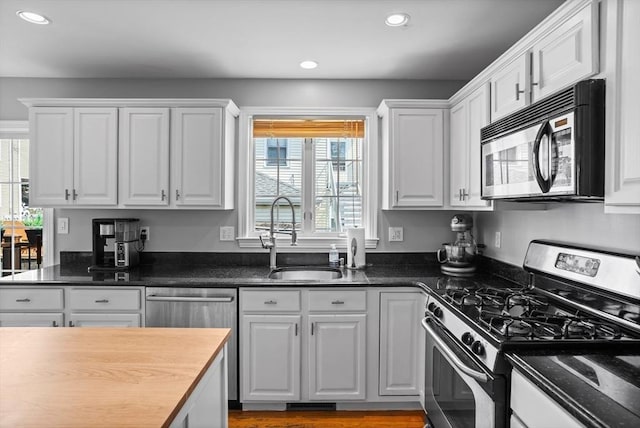 kitchen with sink, white cabinets, stainless steel appliances, and a healthy amount of sunlight