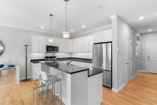 kitchen featuring a center island with sink, white cabinets, light wood-type flooring, and appliances with stainless steel finishes