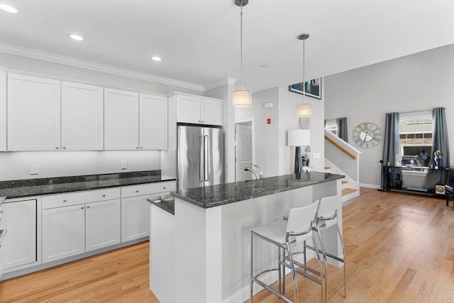 kitchen featuring high end refrigerator, decorative light fixtures, white cabinetry, and light hardwood / wood-style floors