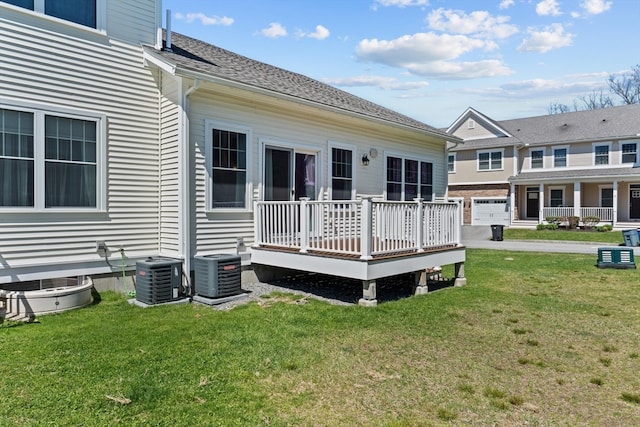 rear view of house featuring central AC unit, a wooden deck, and a lawn