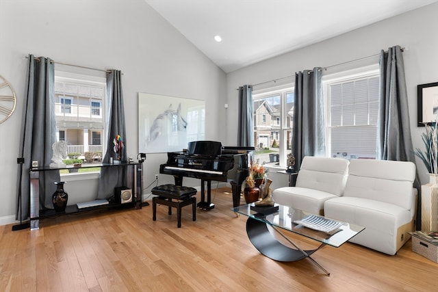 living area featuring light wood-type flooring, high vaulted ceiling, and plenty of natural light