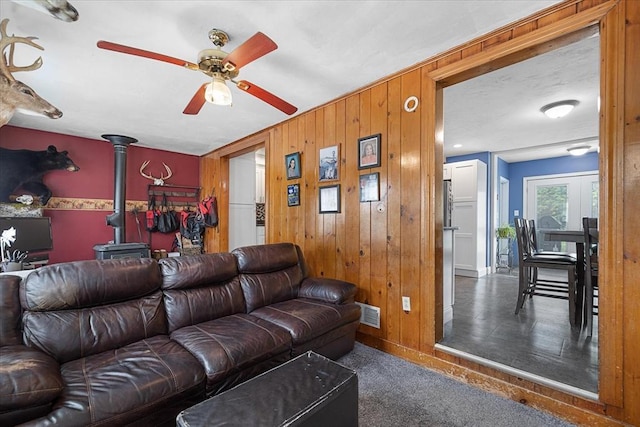 9 Green St, Brookfield, MA 01506 - carpeted living area with a wood stove, ceiling fan, wood walls, and baseboards