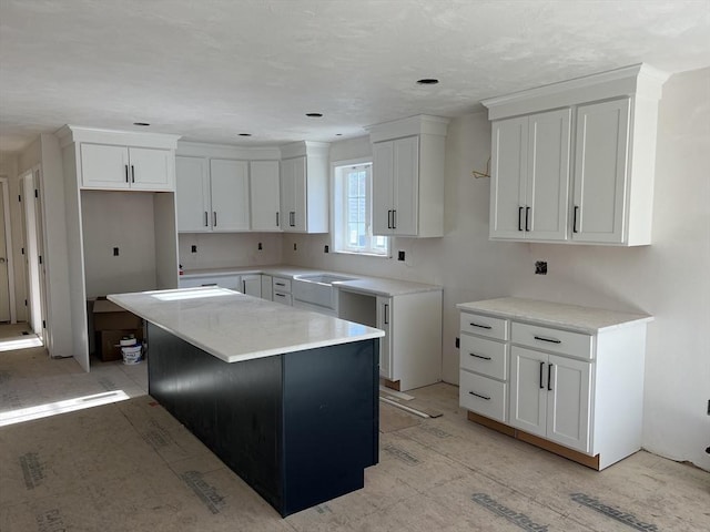 kitchen with sink, white cabinetry, and a kitchen island