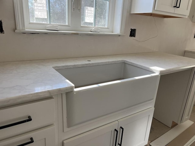 kitchen with white cabinetry and light stone counters