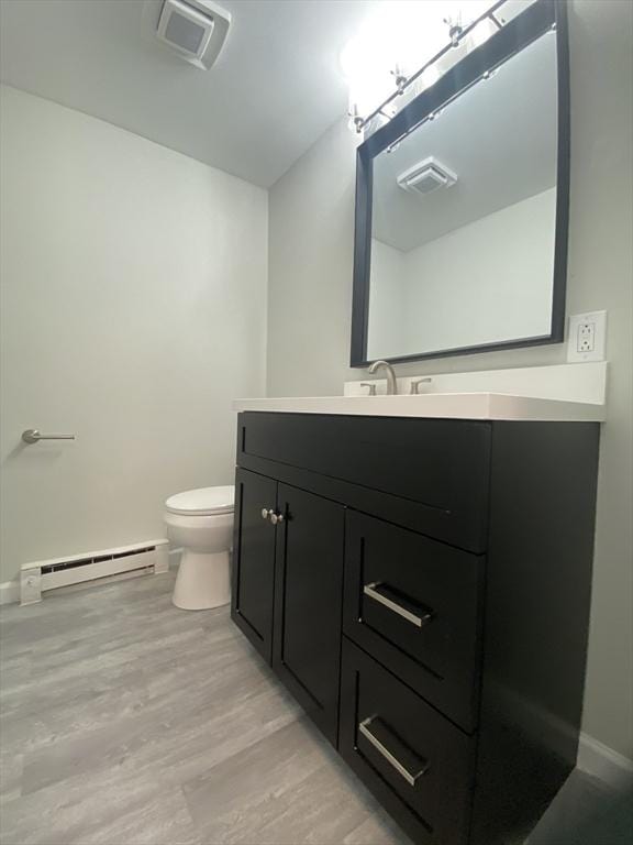 270 Sunderland Rd Unit 11, Worcester, MA 01604 - bathroom with baseboard heating, toilet, vanity, wood finished floors, and baseboards