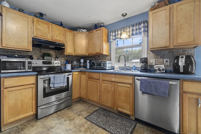 kitchen featuring appliances with stainless steel finishes, under cabinet range hood, a sink, and decorative backsplash