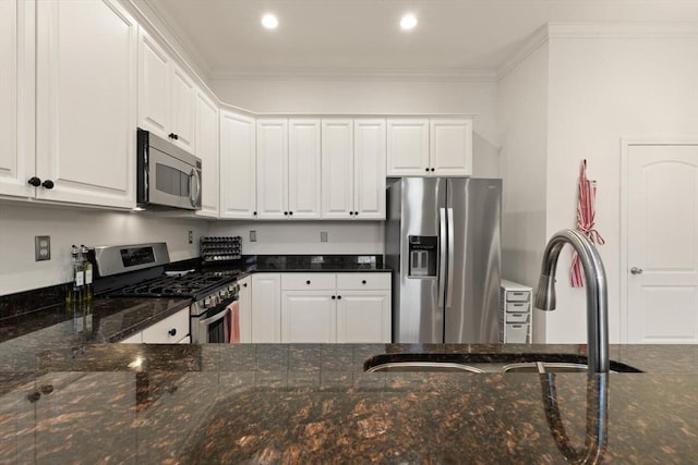 kitchen featuring a sink, dark stone counters, appliances with stainless steel finishes, and white cabinets
