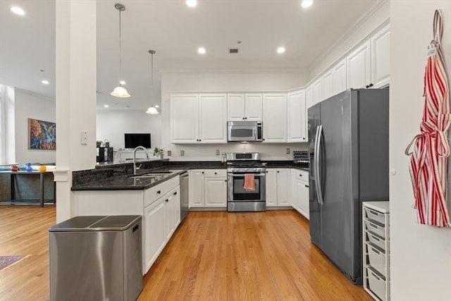 kitchen with a sink, white cabinets, appliances with stainless steel finishes, and a peninsula