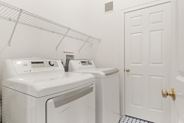 clothes washing area with laundry area, separate washer and dryer, and visible vents