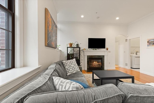 living room with washer and dryer, crown molding, and a healthy amount of sunlight