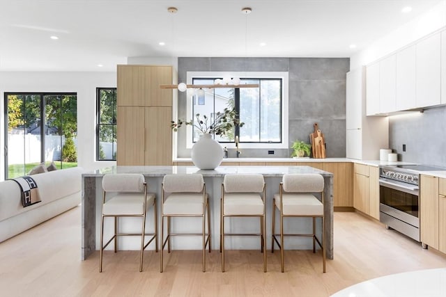 kitchen featuring stainless steel electric stove, a breakfast bar, light hardwood / wood-style flooring, and a wealth of natural light