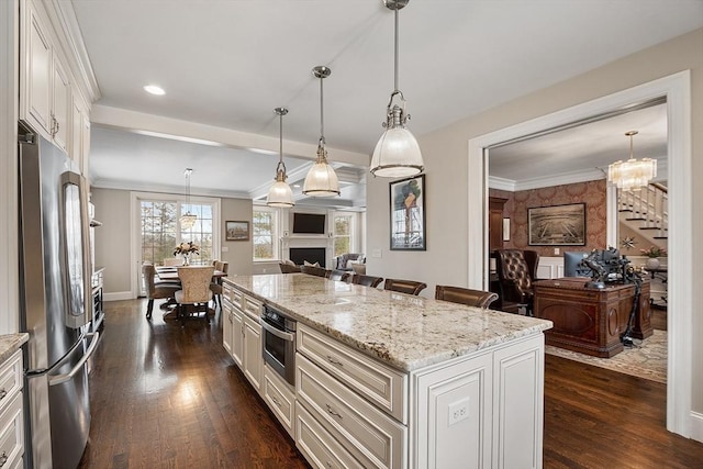 kitchen featuring a kitchen island, open floor plan, decorative light fixtures, stainless steel appliances, and white cabinetry