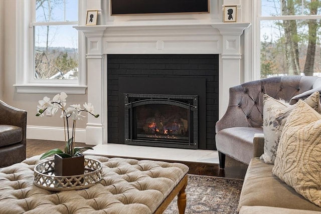 interior space with a fireplace with flush hearth, baseboards, and wood finished floors