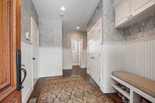 mudroom with wainscoting, dark wood finished floors, visible vents, and wallpapered walls