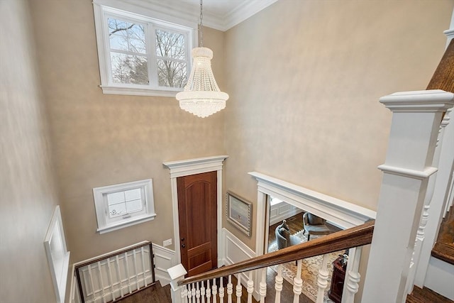 stairs featuring a chandelier, ornamental molding, a high ceiling, and wood finished floors