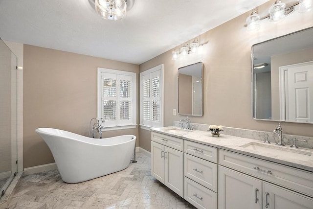 full bathroom featuring a sink, double vanity, baseboards, and a freestanding bath