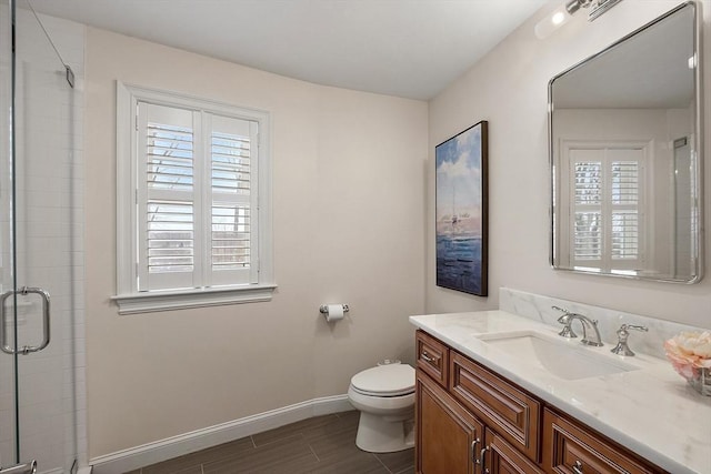 bathroom with toilet, plenty of natural light, vanity, and a shower with door