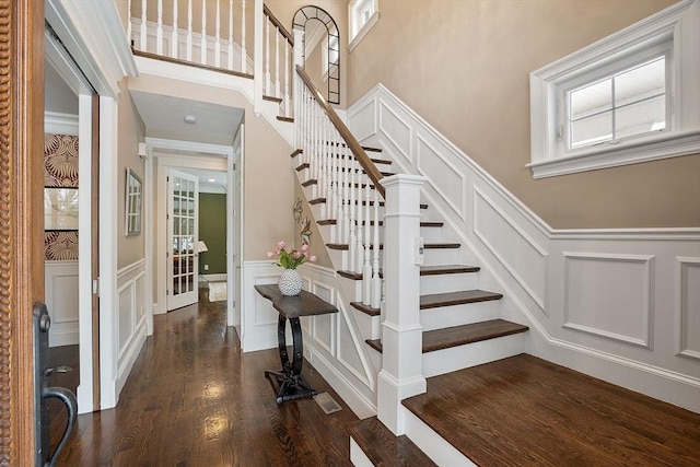 stairs with wood finished floors, visible vents, and a decorative wall