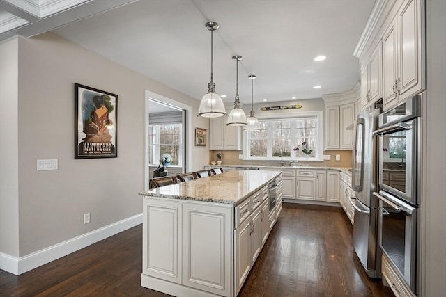 kitchen featuring a kitchen island, white cabinets, hanging light fixtures, light stone countertops, and tasteful backsplash