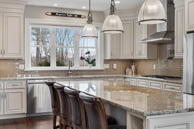 kitchen with appliances with stainless steel finishes, white cabinetry, light stone counters, and wall chimney exhaust hood