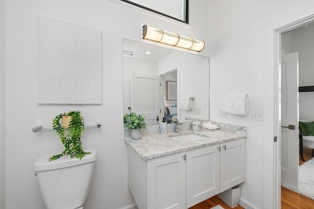 bathroom with wood finished floors, vanity, and toilet