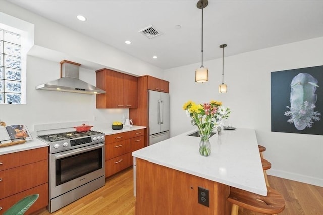 kitchen featuring wall chimney exhaust hood, visible vents, appliances with stainless steel finishes, and light countertops