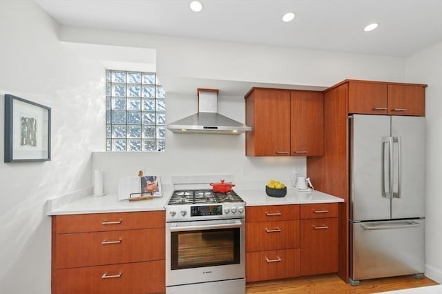 kitchen with recessed lighting, stainless steel appliances, light wood-style floors, light countertops, and wall chimney exhaust hood