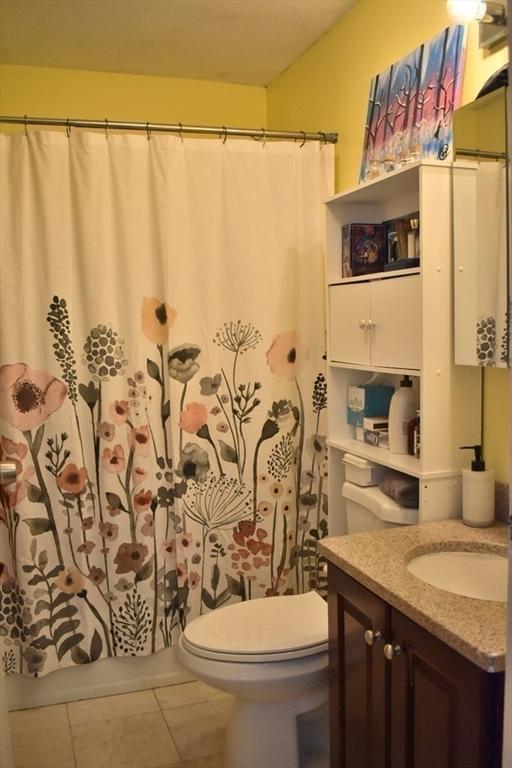full bath featuring tile patterned flooring, a shower with shower curtain, toilet, and vanity