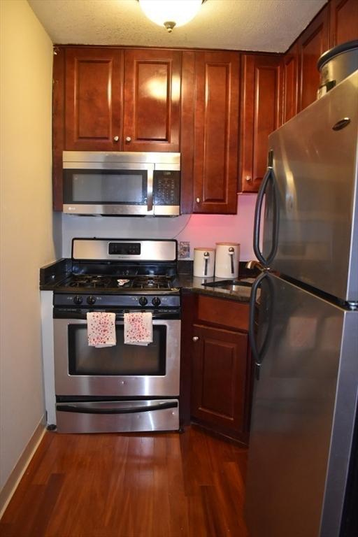 kitchen featuring dark wood finished floors, baseboards, appliances with stainless steel finishes, and a sink
