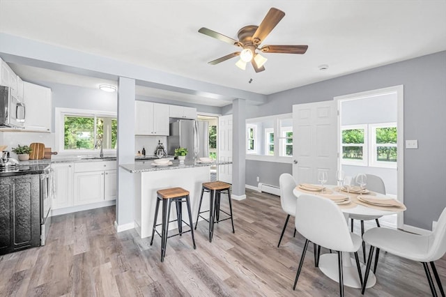 759 Millers Falls Rd, Northfield, MA 01360 - kitchen with appliances with stainless steel finishes, a kitchen island, a kitchen breakfast bar, white cabinetry, and baseboard heating