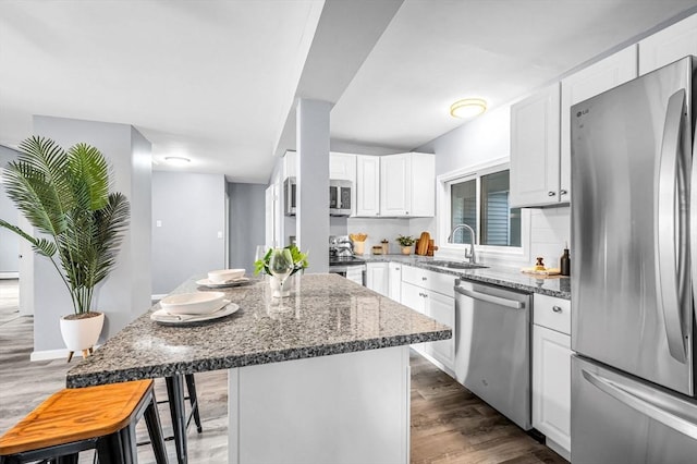 759 Millers Falls Rd, Northfield, MA 01360 - kitchen with stainless steel appliances, dark stone counters, white cabinetry, wood finished floors, and a breakfast bar