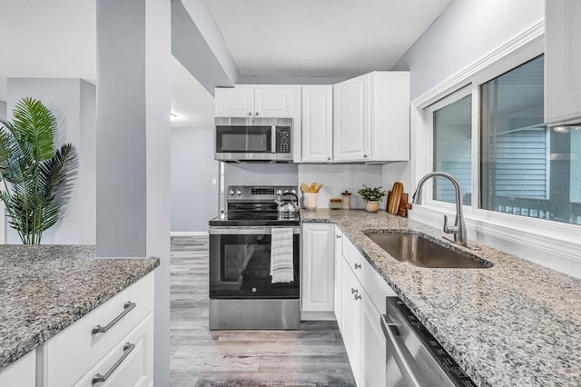 759 Millers Falls Rd, Northfield, MA 01360 - kitchen with appliances with stainless steel finishes, light stone countertops, wood finished floors, and white cabinetry