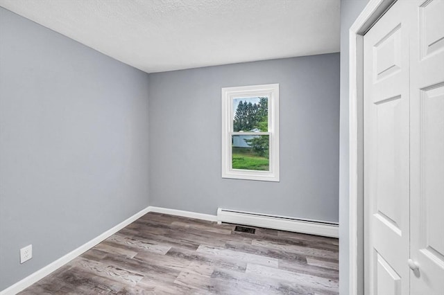 759 Millers Falls Rd, Northfield, MA 01360 - unfurnished room featuring a baseboard heating unit, wood finished floors, and a textured ceiling