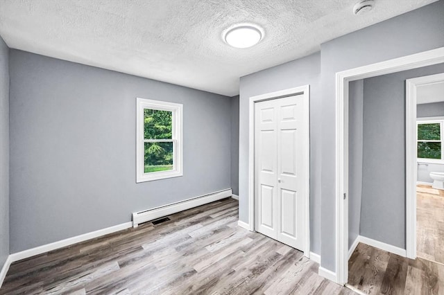 759 Millers Falls Rd, Northfield, MA 01360 - unfurnished bedroom with a baseboard radiator, wood finished floors, a closet, and a textured ceiling