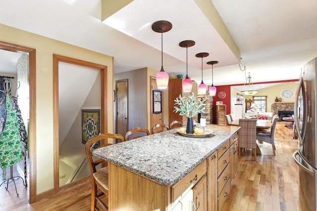 kitchen featuring a kitchen bar, light wood-style floors, freestanding refrigerator, and a center island