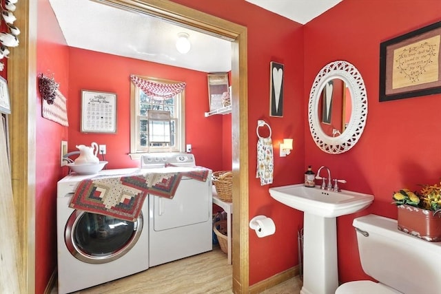 laundry area with washer and dryer, wood finished floors, and a sink