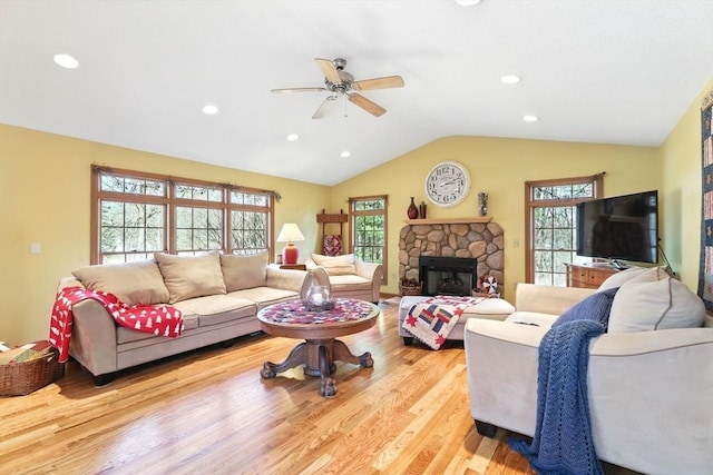 living area with recessed lighting, ceiling fan, a stone fireplace, vaulted ceiling, and light wood-type flooring