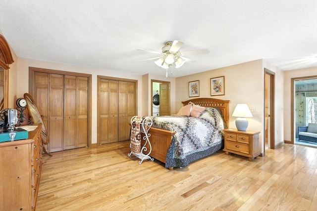 bedroom featuring light wood-style flooring, two closets, stacked washer / drying machine, and ceiling fan