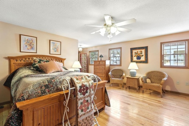 bedroom featuring light wood-type flooring, multiple windows, and a textured ceiling