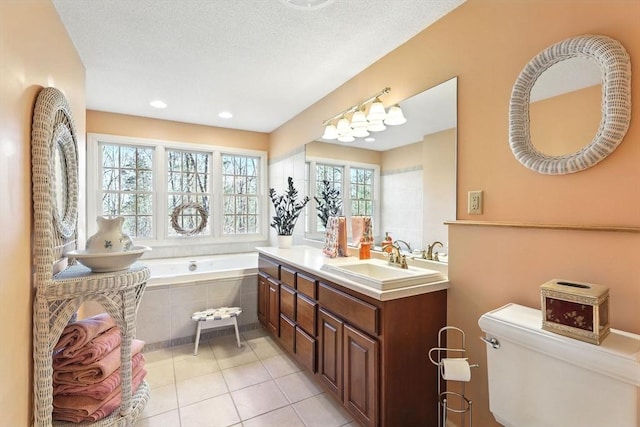 bathroom featuring vanity, a garden tub, a textured ceiling, tile patterned floors, and toilet