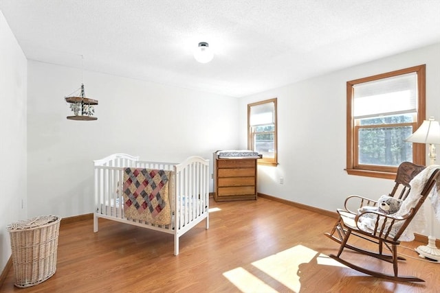 bedroom featuring light wood finished floors, a textured ceiling, and baseboards