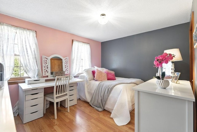 bedroom with light wood-style flooring and a textured ceiling