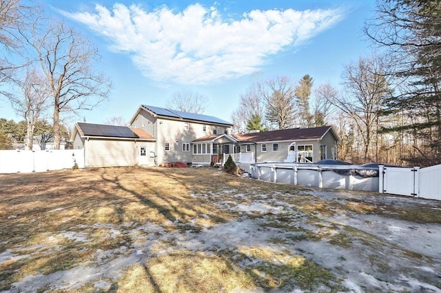 back of house with a fenced backyard, solar panels, a fenced in pool, and a gate