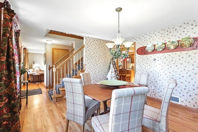 dining space featuring wallpapered walls, light wood-style floors, and a chandelier