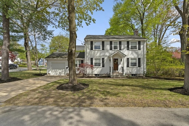 colonial inspired home featuring an attached garage, concrete driveway, a chimney, and a front yard