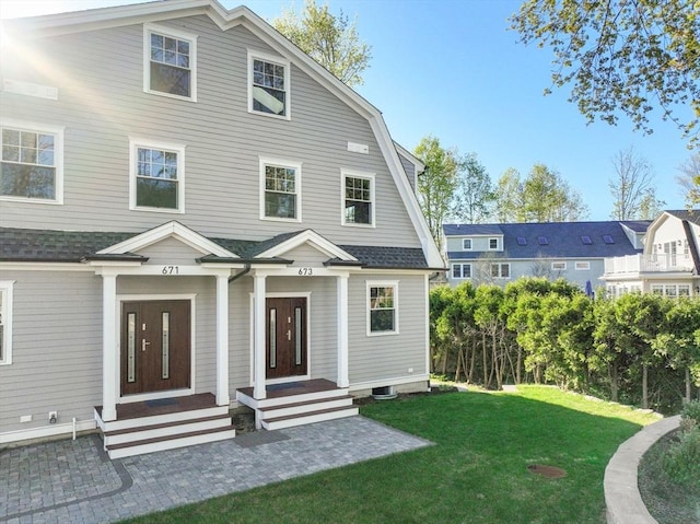 back of property featuring a shingled roof and a yard